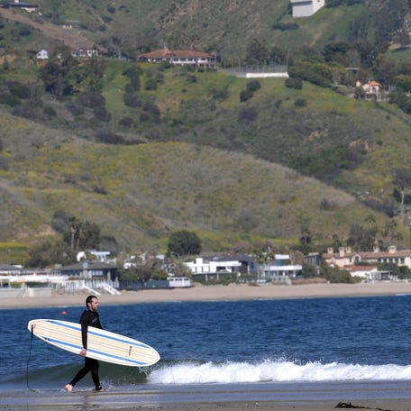 A surfer heads toward the water at Laguna Beach in Malibu, California, on April 3, 2009. Malibu's myriad beaches draw a large number of tourists and surfers from across the country.