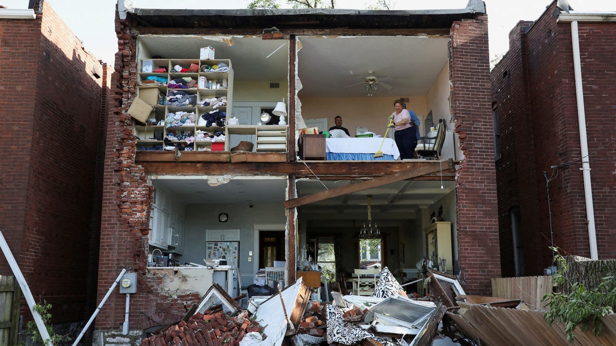 Residents inspect their home after a tornado completely tore off the back wall of a two-story house in St. Louis, Missouri, on May 16, 2025.