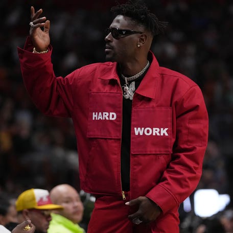 Former NFL player Antonio Brown gestures to the fans while standing in from t of former professional boxer Floyd Mayweather Jr. during the second half between the Miami Heat and the Brooklyn Nets at FTX Arena in Miami on March 26, 2022.