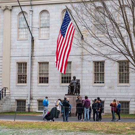 People gather around the John Harvard Statue on the Harvard University campus in Cambridge, Massachusetts, on April 15, 2025.
