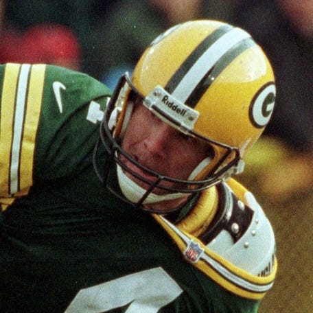 Green Bay Packers quarterback Brett Favre is able to get off a pass despite being dragged by Detroit Lions Luther Ellis during the second quarter of their game on Dec. 10, 2000 at Lambeau Field in Green Bay, Wis.