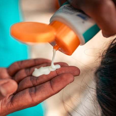 Close-up view of a man's hands as he skillfully squeezes sunscreen from a tube.