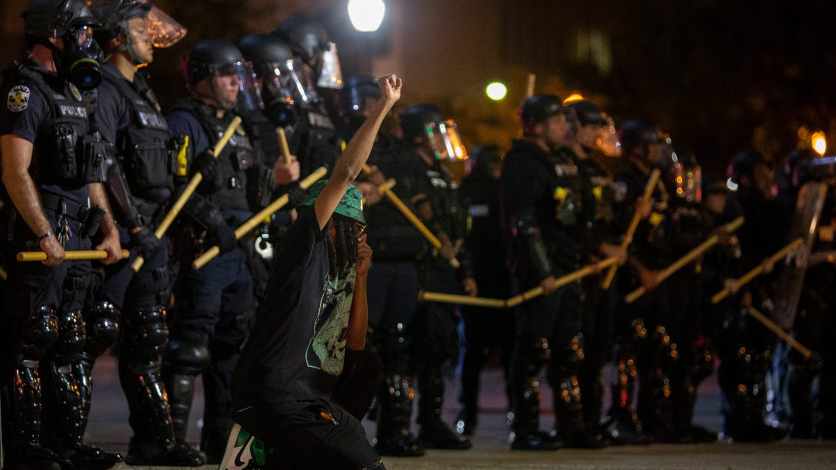 Scenes from a protest in downtown Louisville over the shooting of Breonna Taylor by Louisville police. A lone protester kneels in front of Louisville Metro police officers at Sixth and Jefferson streets. May 28, 2020