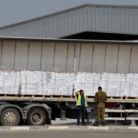 An Israeli security forces member speaks to a worker next to a truck carrying aid at the Kerem Shalom crossing between Israel and Gaza, before going into Gaza, May 22, 2025.