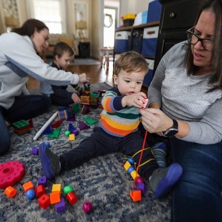 Macklan Trainor, 1, gets help from mom Sally Trainor placing his blocks through a string while playing in the living room with his mom Leanne Trainor, 42, and brother Gabriel, 4, at their home in Plymouth, Mich. on Saturday, Feb. 4, 2023.