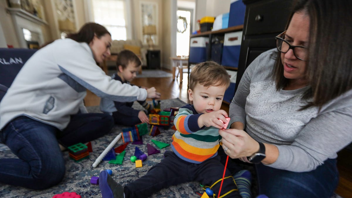Macklan Trainor, 1, gets help from mom Sally Trainor placing his blocks through a string while playing in the living room with his mom Leanne Trainor, 42, and brother Gabriel, 4, at their home in Plymouth, Mich. on Saturday, Feb. 4, 2023.