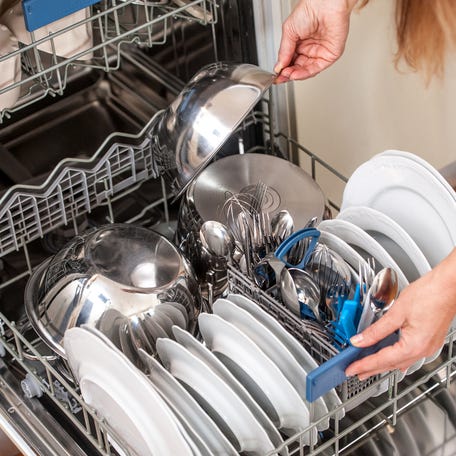 A woman unloads the dishwasher in the kitchen.
