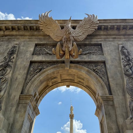 A phoenix and other magic creatures adorn the towering archway at Universal Epic Universe's Wizarding World of Harry Potter – Ministry of Magic.