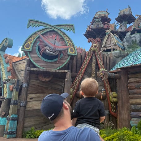 A young child stares at one of the many dragons built into the landscape of Universal Epic Universe's How to Train Your Dragon – Isle of Berk.