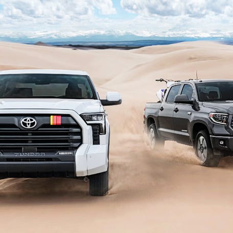 Two 2025 Toyota Tundra full-size pickup trucks are driving in the sand.