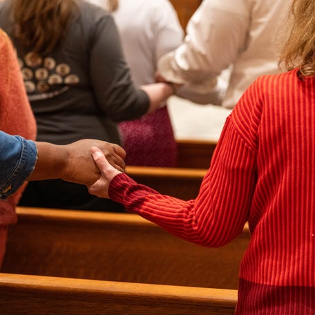 Parishioners hold hands with thy neighbors during Mass at the University of Mount Saint Vincent in Riverdale, N.Y. on May 29, 2025.