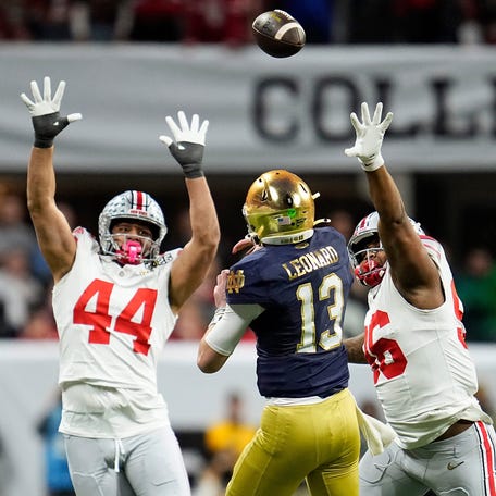 Notre Dame quarterback Riley Leonard passes between Ohio State's JT Tuimoloau (44) and Eddrick Houston during the CFP championship game in January.