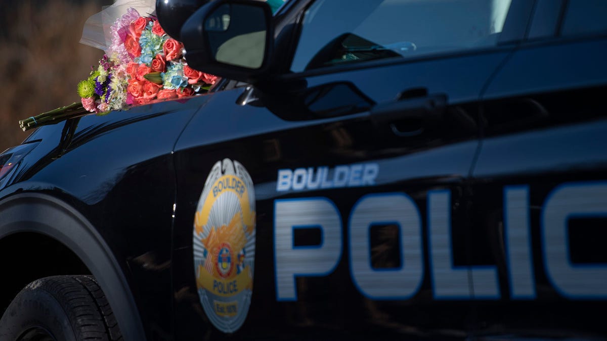 Flowers sit on the hood of a patrol car during a news conference at the Boulder Police Department in Boulder, Colorado.