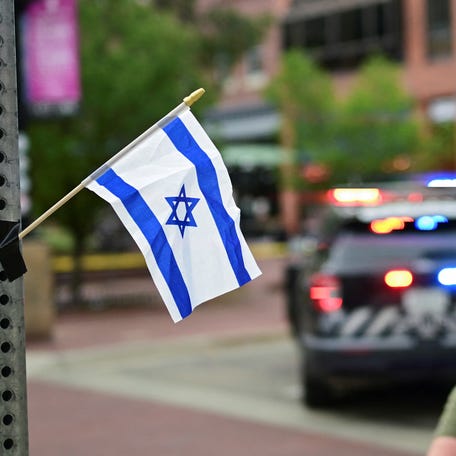 Sam King crosses the street after affixing an Israeli flag to a street light near the scene of an attack that injured multiple people, in Boulder, Colorado on June 1, 2025.