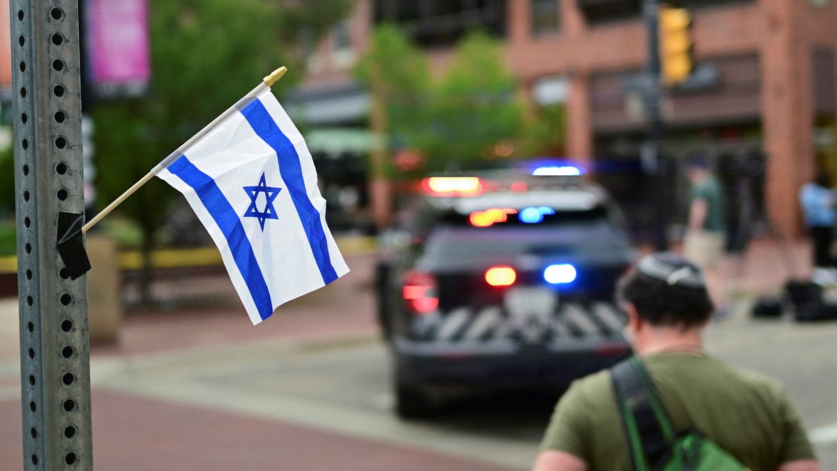 Sam King crosses the street after affixing an Israeli flag to a street light near the scene of an attack that injured multiple people, in Boulder, Colorado on June 1, 2025.