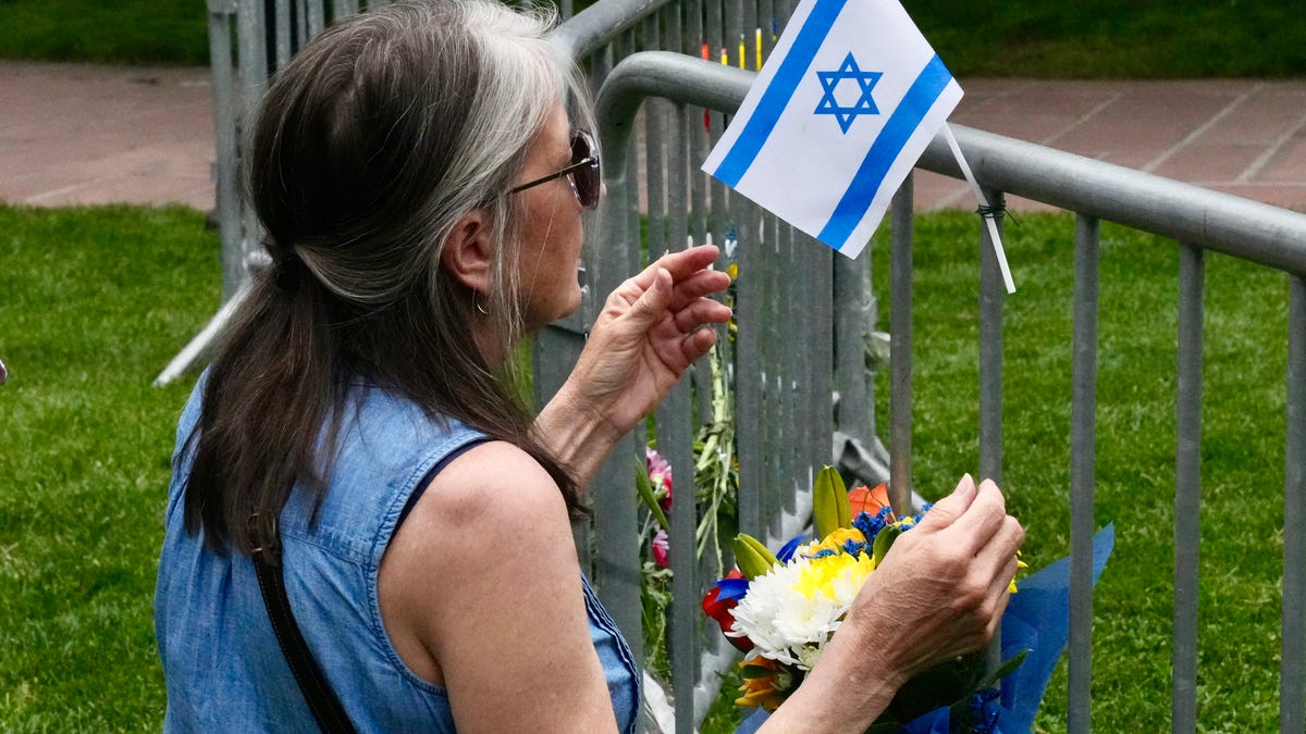 Witness Lisa Turnquist, 66, pauses for a moment after attaching an Israeli flag and a bouquet of flowers at a small memorial in Boulder, Colorado, on June 2, 2025, a day after a terror attack on a pro-Israel march. Turnquist said she helped smother the flames on a woman's legs with a towel from her dog's stroller.