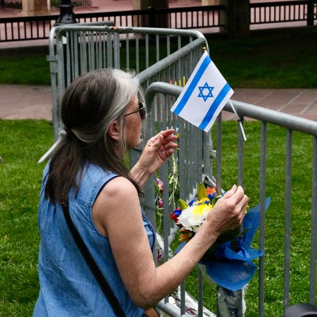 Witness Lisa Turnquist, 66, pauses for a moment after attaching an Israeli flag and a bouquet of flowers at a small memorial in Boulder, Colorado, on June 2, 2025, a day after a terror attack on a pro-Israel march. Turnquist said she helped smother the flames on a woman's legs with a towel from her dog's stroller.