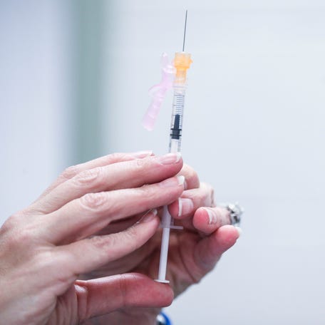 A nurse readies a syringe during a free vaccination event for students and faculty at Iroquois High School. The event was voluntary for those wishing to receive vaccinations for measles and Covid-19.