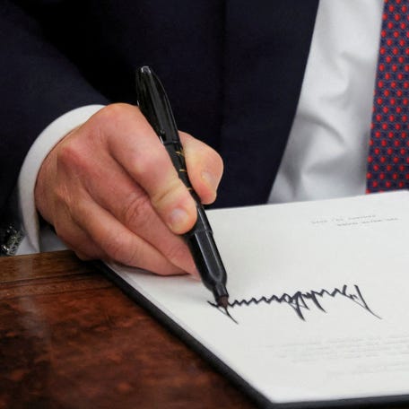 U.S. President Donald Trump signs documents as he issues executive orders and pardons for January 6 defendants in the Oval Office at the White House on Inauguration Day in Washington, U.S., January 20, 2025.