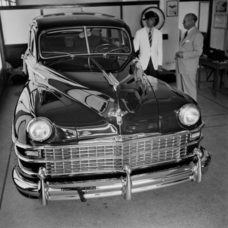 Two men stand on the far side of a Chrysler Windsor on display (4,500 USD or 140,000 pesetas) at a motor showroom in Tangier, Morocco, 1948.