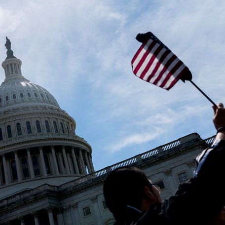 A visitor waves an American flag near the U.S. Capitol, as the U.S. House of Representatives considers U.S. President Donald Trump's sweeping tax-cut bill, on Capitol Hill in Washington, D.C., U.S., May 19, 2025.