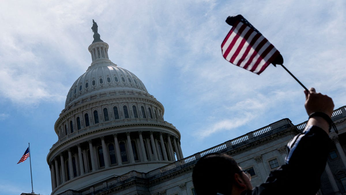 A visitor waves an American flag near the U.S. Capitol, as the U.S. House of Representatives considers U.S. President Donald Trump's sweeping tax-cut bill, on Capitol Hill in Washington, D.C., U.S., May 19, 2025.