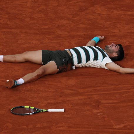 An exhausted Carlos Alcaraz of Spain collapses after winning the 2025 French Open title, beating Jannik Sinner of Italy in a record 5 hours, 29 minutes.