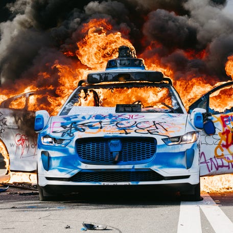 A Waymo car burns in the street as smoke billows during protests in Los Angeles, California, on June 8, 2025.