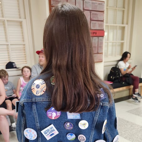 A National History Day participant shows off the pins she has collected from students who live in other states.