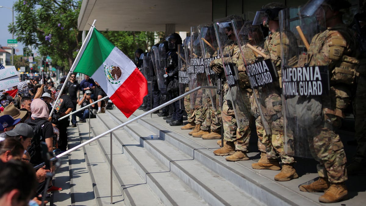 A demonstrator waves a Mexico flag in front of California National Guard troops, as protests against immigration sweeps continue, in Los Angeles, California, U.S. June 9, 2025.