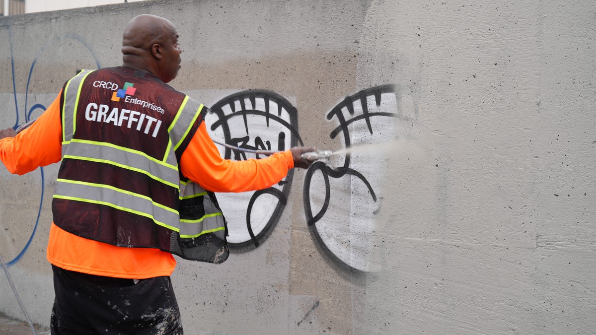 PainterÕs apprentice Tim Brevard, 53, paints over graffiti in downtown Los Angeles on June 10, 2025, following protests about immigration enforcement. Brevard and his team normally have to remove gang-related graffiti from the area each day, but the protest-related graffiti has added to their workload.