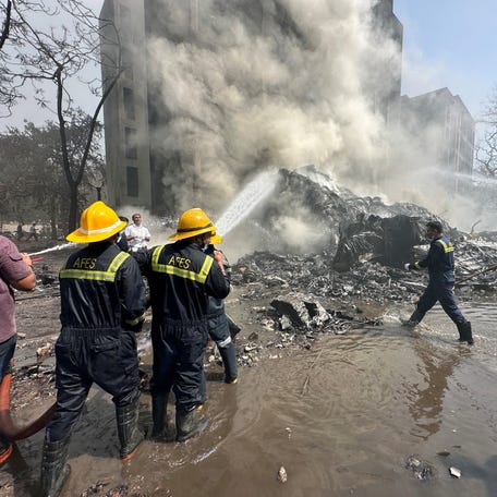 Rescue team members work as smoke rises at the site where an Air India plane crashed in Ahmedabad, India, June 12, 2025.
