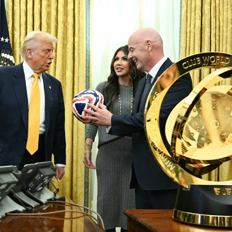 US President Donald Trump, FIFA president Gianni Infantino and US Secretary of Homeland Security Kristi Noem look at new FIFA Club World Cup trophy and official ball in the Oval office of the White House, in Washington, DC, on March 7, 2025.