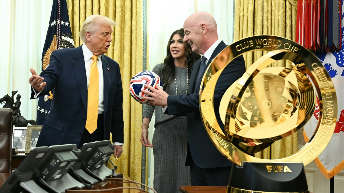 US President Donald Trump, FIFA president Gianni Infantino and US Secretary of Homeland Security Kristi Noem look at new FIFA Club World Cup trophy and official ball in the Oval office of the White House, in Washington, DC, on March 7, 2025.