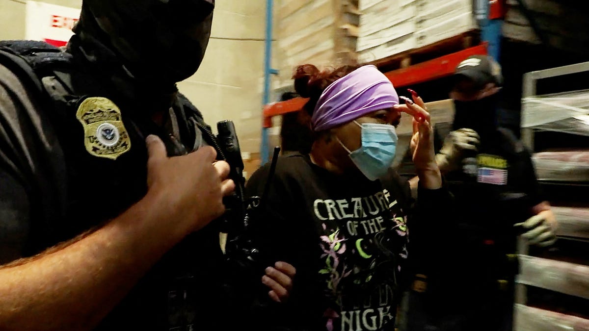A woman is detained during a raid by Immigration and Customs Enforcement (ICE) at a Glenn Valley Foods meat production plant in Omaha, Nebraska