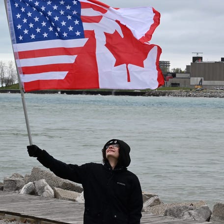 Marcello Asaro waves a U.S./Canadian flag along the St. Clair River on April 26, 2025.