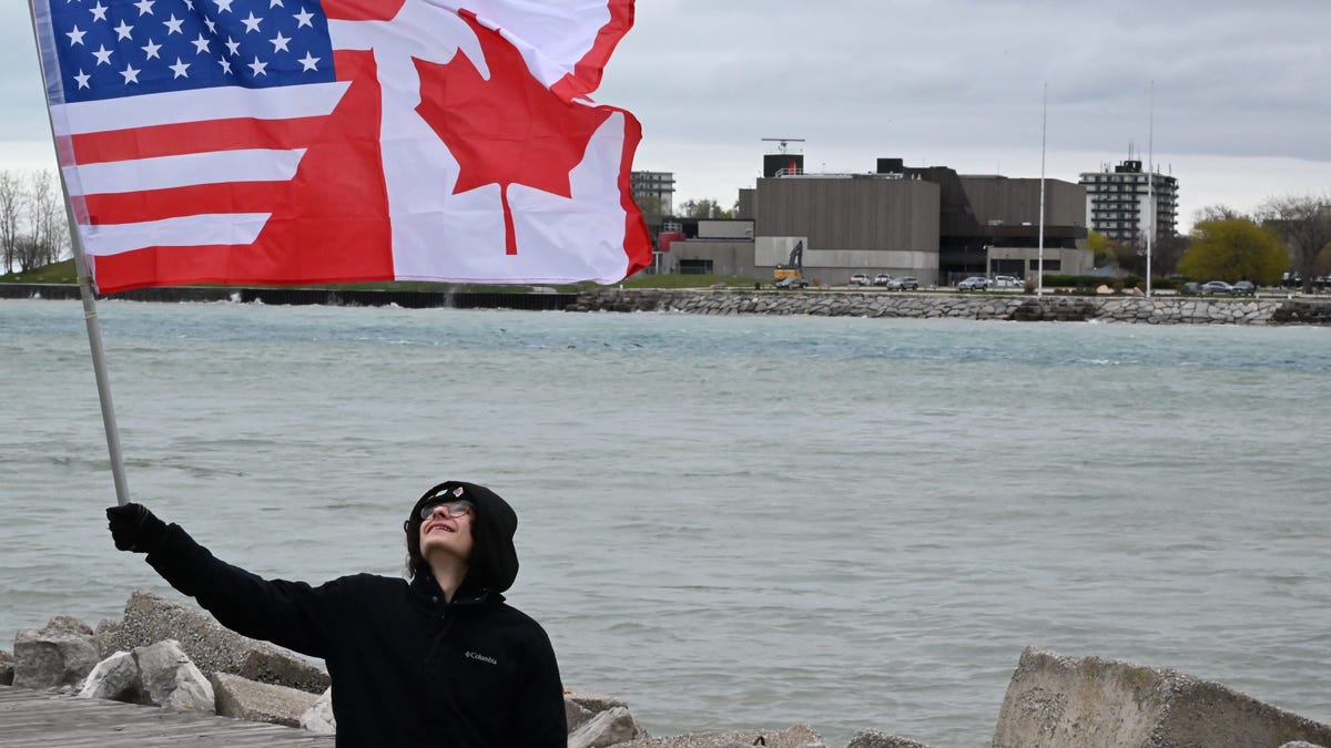 Marcello Asaro waves a U.S./Canadian flag along the St. Clair River on April 26, 2025.
