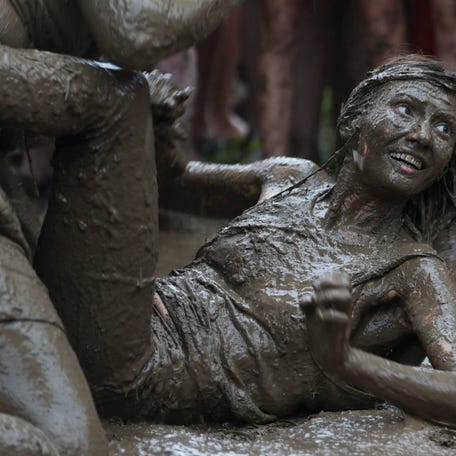 Mud wrestlers pause for a moment in the muck in Outer on The Farm during Bonnaroo Music and Arts Festival, in Manchester, Tennessee on June 13, 2025. Heavy rain led organizers to cancel the rest of the festival.