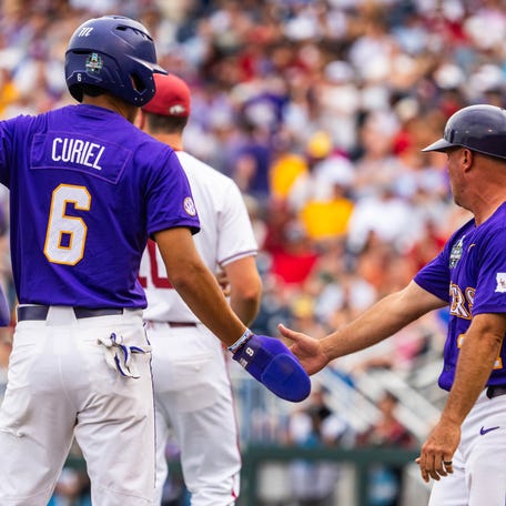 Jun 14, 2025; Omaha, Neb, USA; LSU Tigers assistant coach Josh Jordan and left fielder Derek Curiel (6) celebrate after a score during the second inning against the Arkansas Razorbacks at Charles Schwab Field. Mandatory Credit: Dylan Widger-Imagn Images