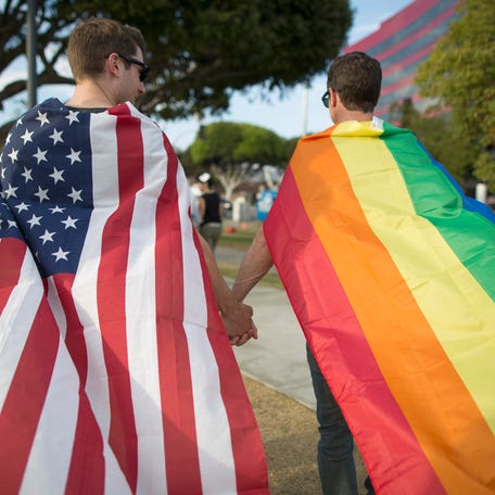 Robert Oliver and Mark Heller (R) hold hands, draped in flags, as they celebrate the Supreme Court ruling on same-sex marriage on June 26, 2015 in West Hollywood, California. The Supreme Court ruled today that same-sex couples have a constitutional right to marry nationwide without regard to their state's laws.