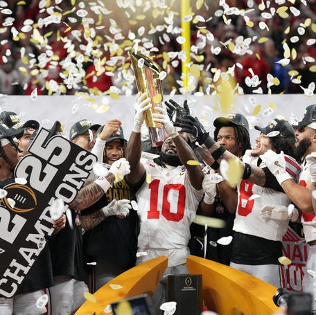 Ohio State's Denzel Burke (10) hoists the College Football Playoff national championship trophy after the Buckeyes beat Notre Dame. The playoff will stay at 12 teams in 2025. Then, the format is undecided. The Big Ten and SEC might be forced to work to a compromise.