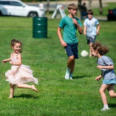 Children playing on the green at the opening day of the Framingham Farmers Market on the Framingham Centre Common on June 19, 2025.