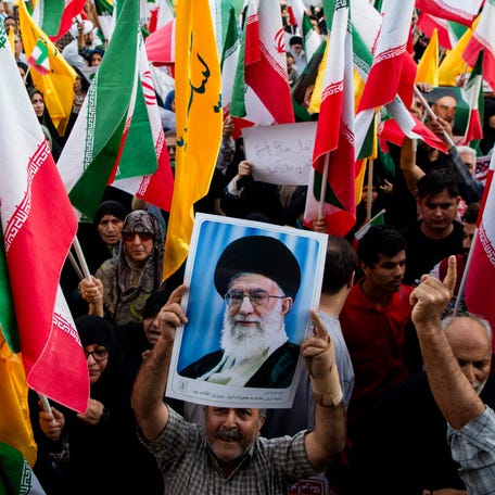 People are pictured holding flags of Iran and Hezbollah, as well as posters of Supreme Leader Ayatollah Ali Khamenei, in downtown Enghelab (Revolution) Square in Tehran.