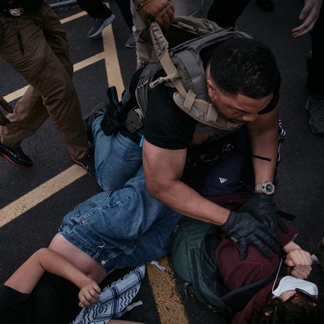 A Federal agent holds back his colleague as he pins down a protestor during a protest over federal immigration enforcement raids at Delaney Hall Detention Facility on June 13, 2025 in Newark, New Jersey.