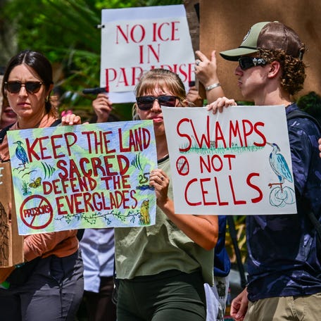 Demonstrators hold signs as they protest the construction of an immigrant detention center, dubbed "Alligator Alcatraz," in the Everglades near Ochopee, Florida, on June 28, 2025. Florida began construction this week on a detention center surrounded by fierce reptiles and cypress swamps, an "Alligator Alcatraz" in the Everglades wetlands, as part of US President Donald Trump's expansion of deportations of undocumented migrants.   The chosen site, an abandoned airfield in the heart of a sprawling network of mangrove forests, imposing marshes and "rivers of grass" that form the conservation area, will house large tents and beds for 1,000 "criminal aliens," according to state Attorney General James Uthmeier.