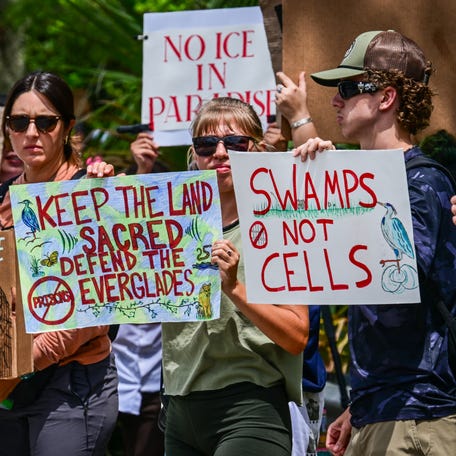 Demonstrators hold signs as they protest the construction of an immigrant detention center, dubbed "Alligator Alcatraz," in the Everglades near Ochopee, Florida, on June 28, 2025. Florida began construction this week on a detention center surrounded by fierce reptiles and cypress swamps, an "Alligator Alcatraz" in the Everglades wetlands, as part of US President Donald Trump's expansion of deportations of undocumented migrants.   The chosen site, an abandoned airfield in the heart of a sprawling network of mangrove forests, imposing marshes and "rivers of grass" that form the conservation area, will house large tents and beds for 1,000 "criminal aliens," according to state Attorney General James Uthmeier.