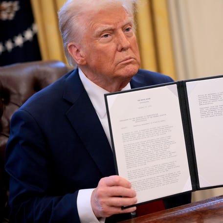 President Donald Trump hold up a memorandum he signed ordering an immediate assessment of aviation safety and ordering an elevation of what he called "competence over DEI."