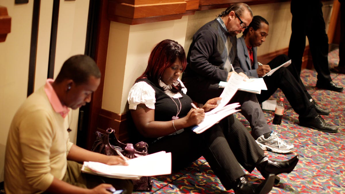 People fill up job application forms at a job fair in Los Angeles, California.