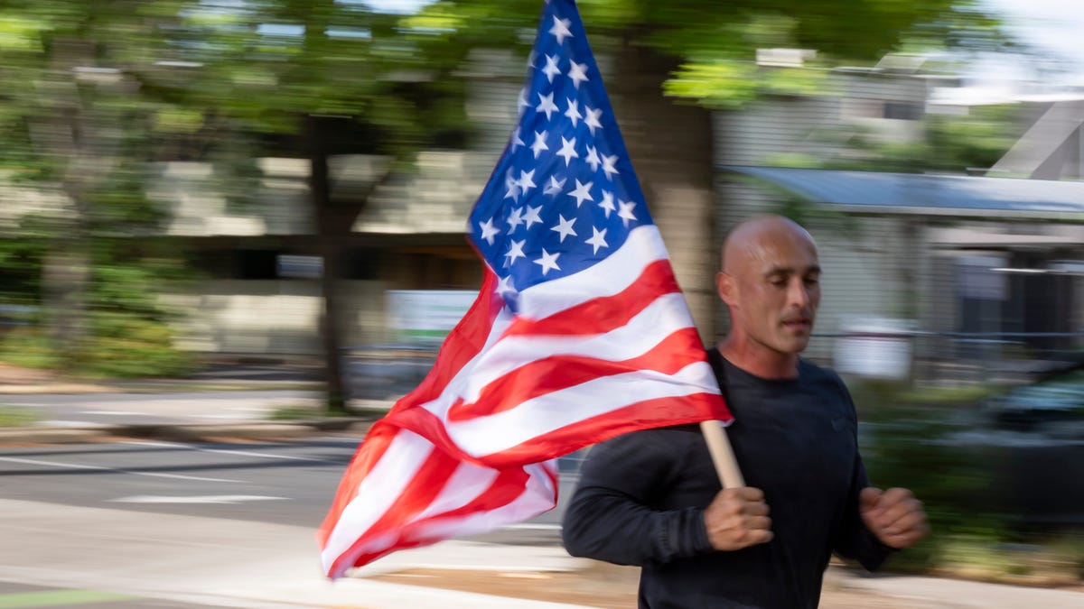 Frank Folino carries an American flag during the annual Oregon Track Club Butte to Butte on July 4, 2025, in Eugene, Ore.