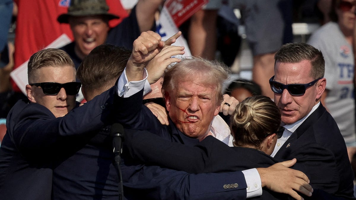 President Donald Trump is assisted by the Secret Service after gunfire rang out during a campaign rally at the Butler Farm Show in Butler, Pennsylvania, U.S., July 13, 2024.